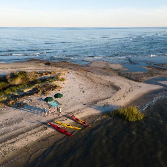 Aerial shot of family walking on beach after kayaking