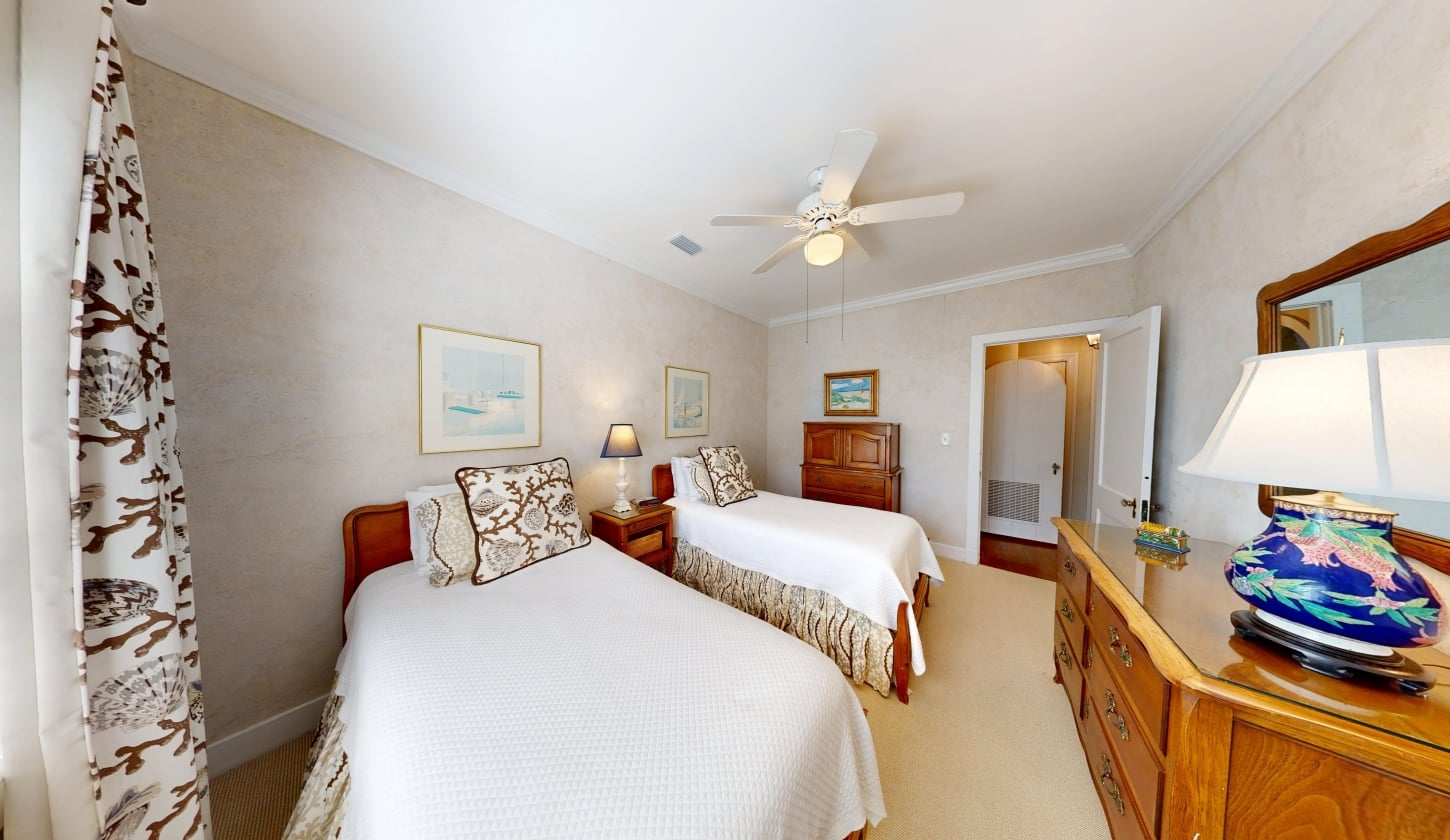 A bedroom with two beds and a ceiling fan