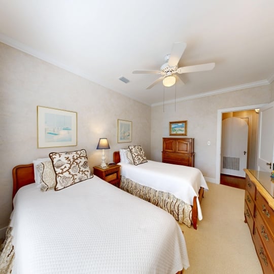 A bedroom with two beds and a ceiling fan