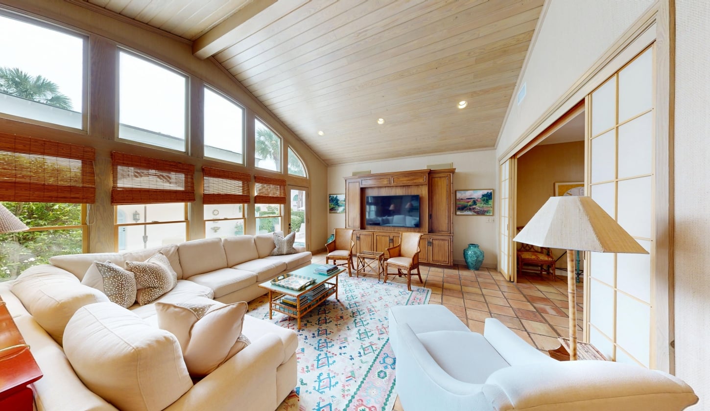 A spacious family room with tall floor-to-ceiling windows and a fireplace