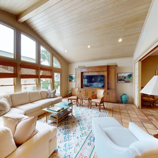 A spacious family room with tall floor-to-ceiling windows and a fireplace