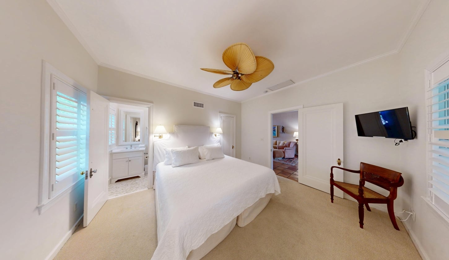 A white bedroom with a king bed and ceiling fan