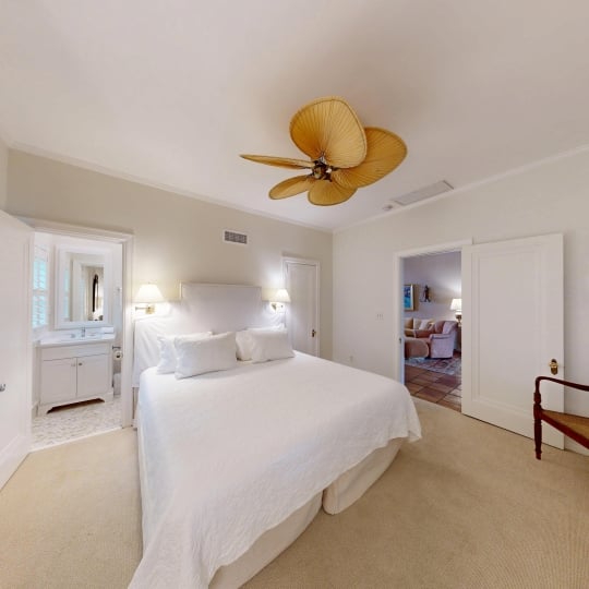 A white bedroom with a king bed and ceiling fan