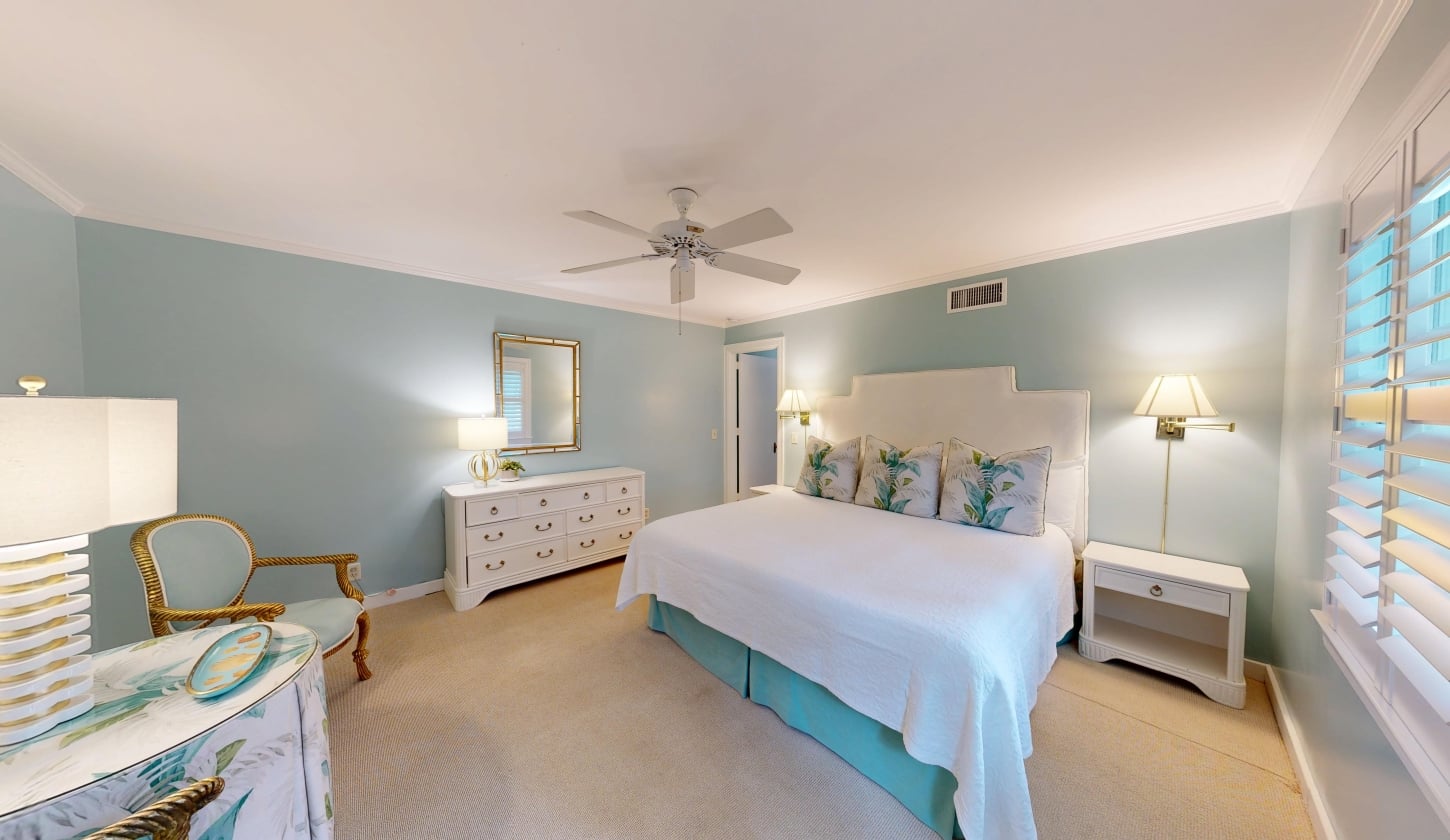 A king bed with a white dresser beside it