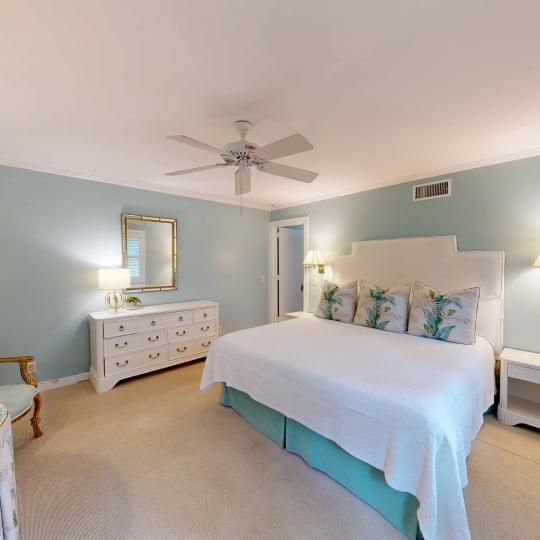 A king bed with a white dresser beside it
