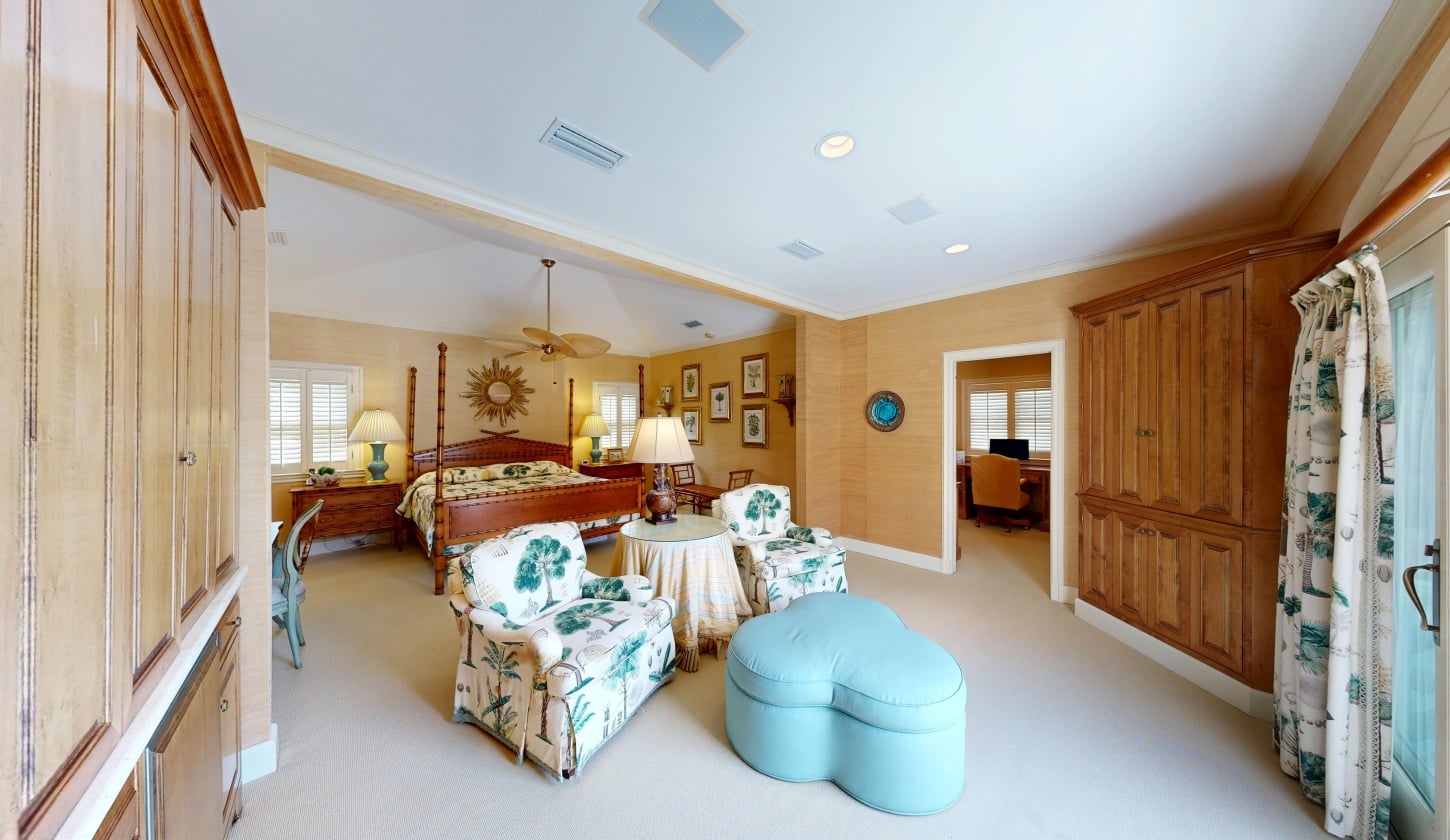 A primary bedroom with a seating area facing large windows
