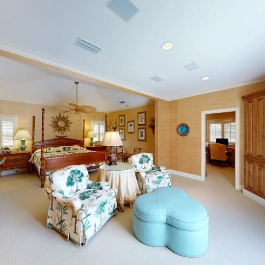 A primary bedroom with a seating area facing large windows