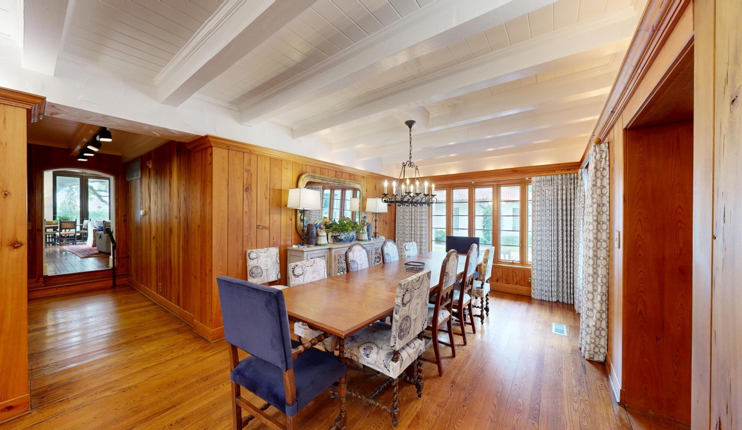 A dining room with a long table and small chandelier
