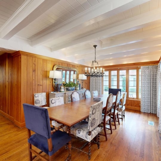 A dining room with a long table and small chandelier