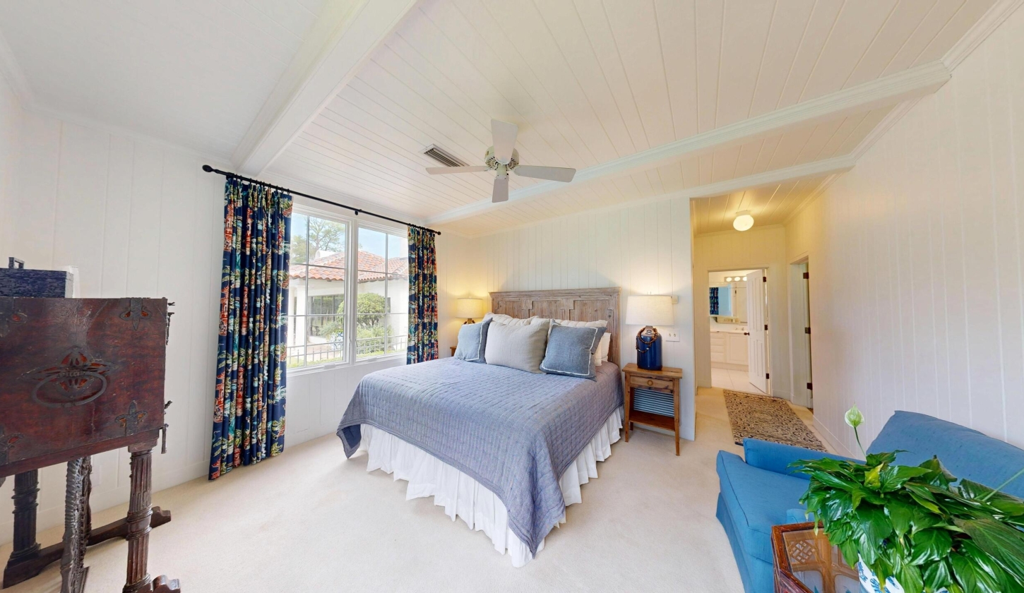 A large bed with big windows and a ceiling fan