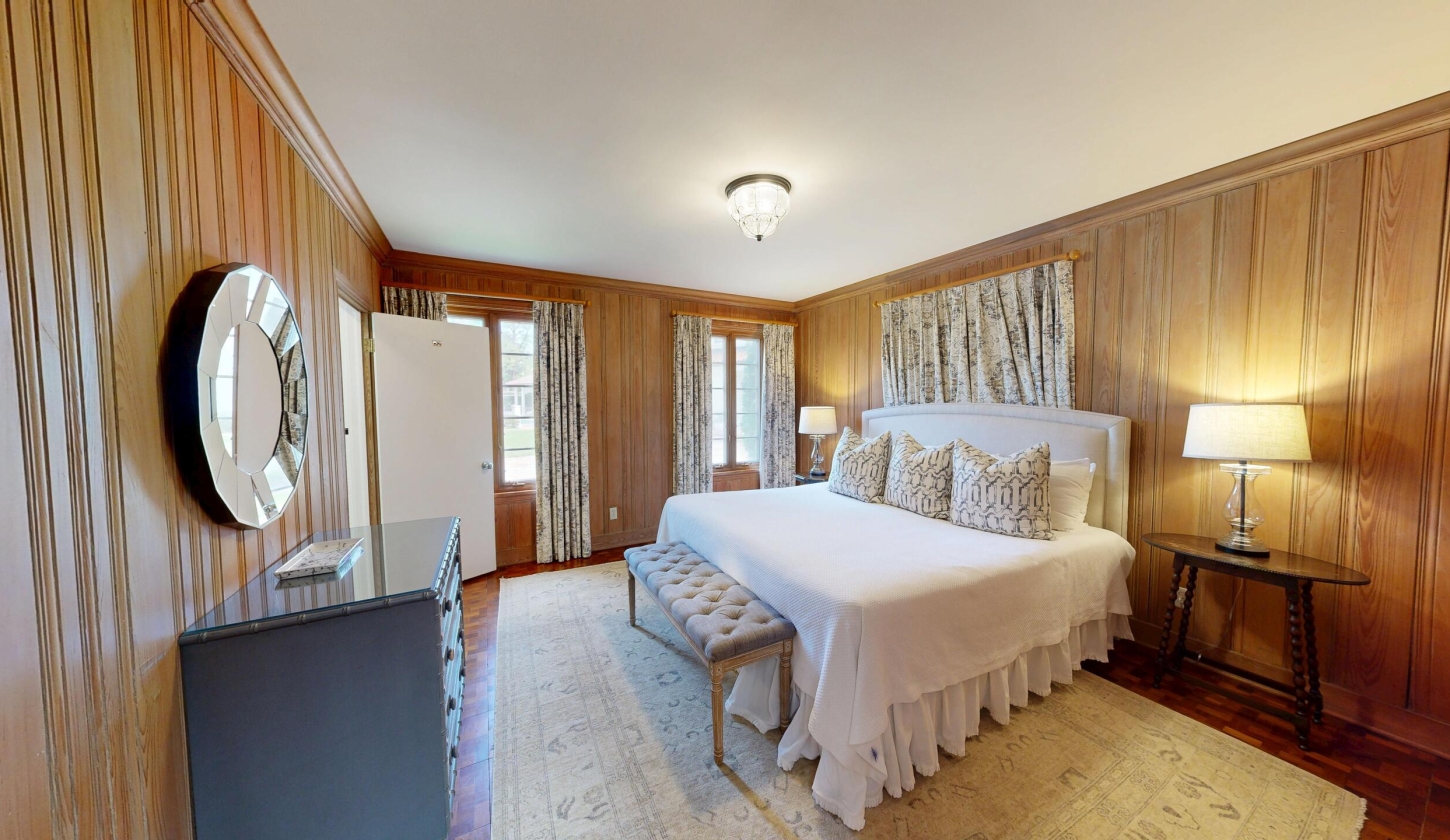 A king bed sits in a cosy room with a dresser