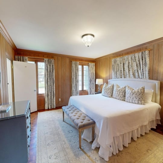 A king bed sits in a cosy room with a dresser