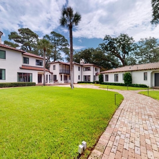 The walkway leading up to a home with trees behind it
