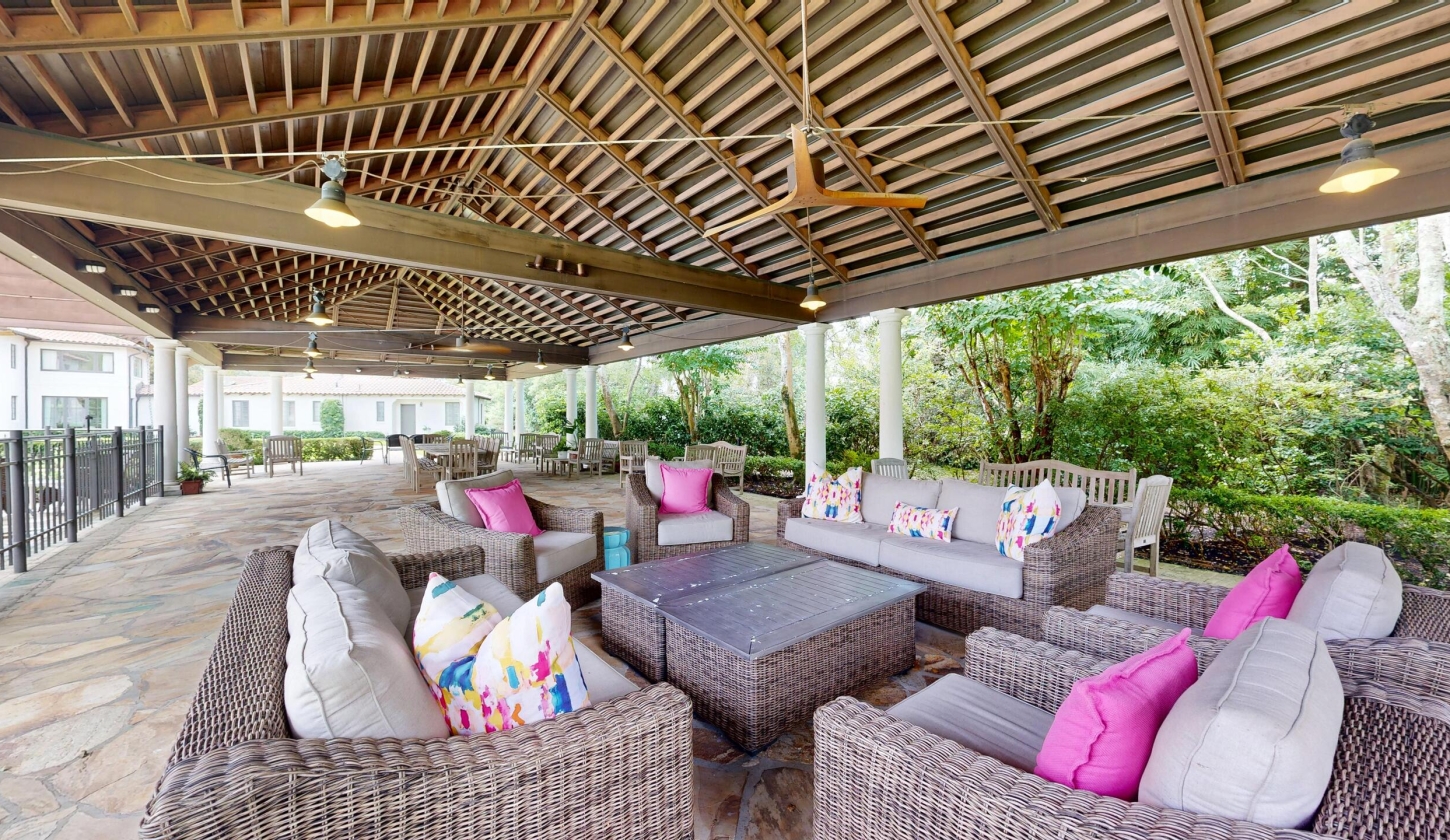 A covered patio with a ceiling fan and ample seating