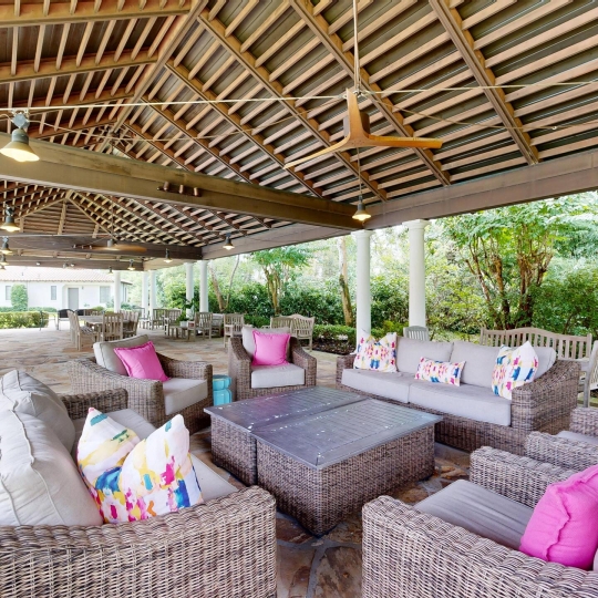 A covered patio with a ceiling fan and ample seating