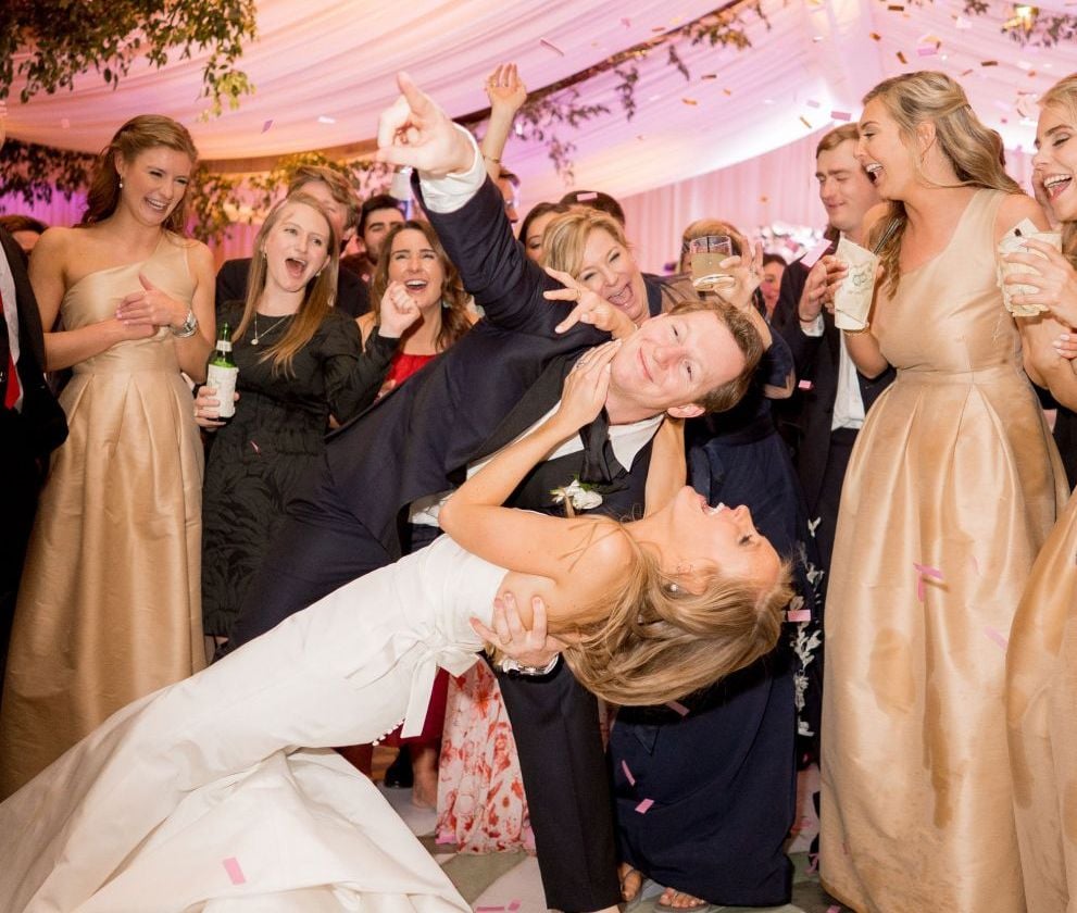 groom dipping wife while dancing in front of friends