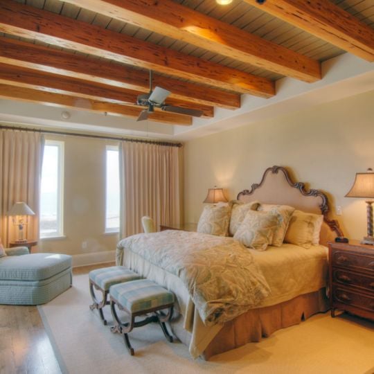 Bedroom with light blue chair and exposed wood ceiling