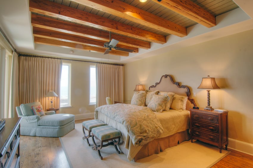 Bedroom with light blue chair and exposed wood ceiling