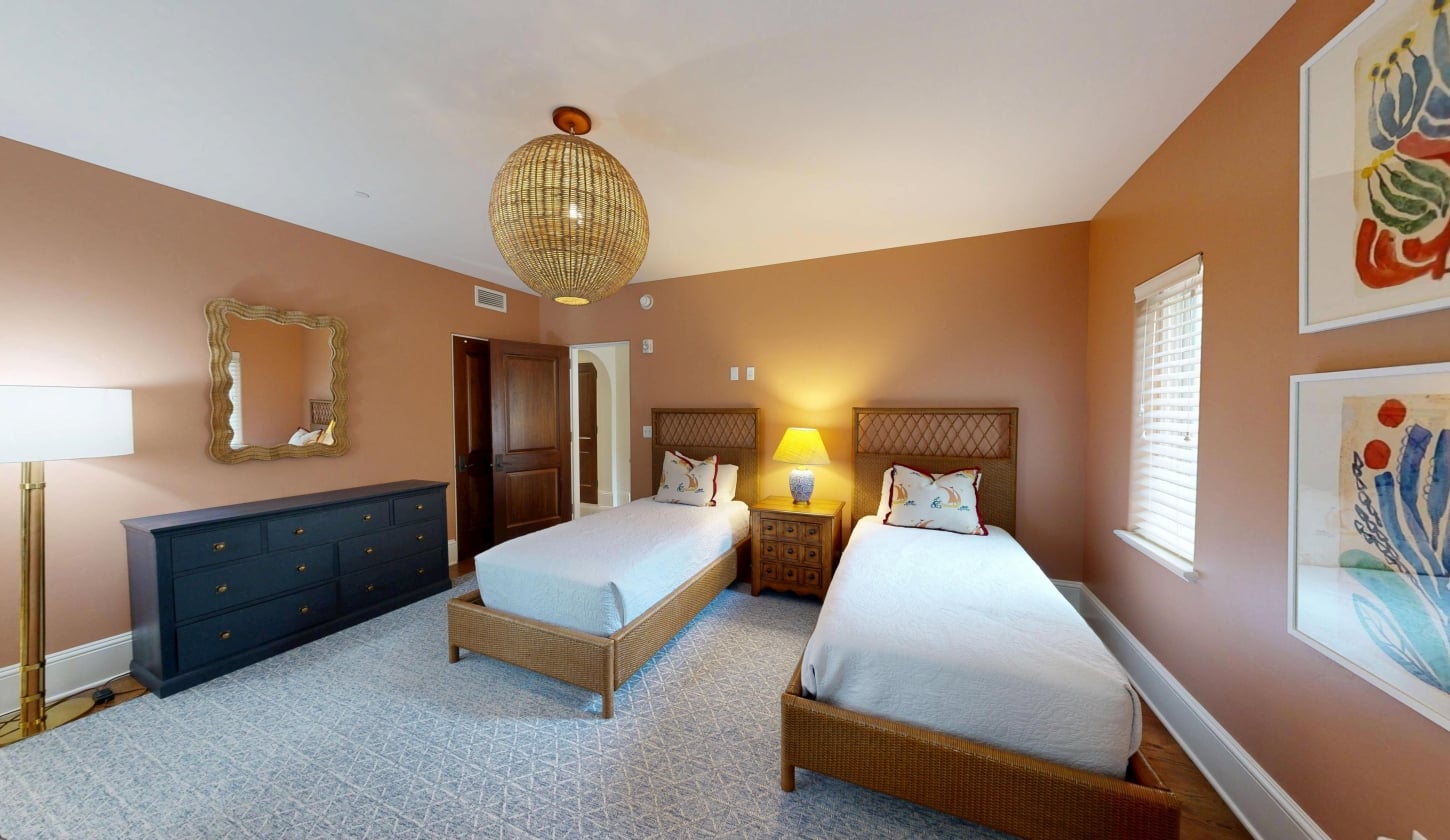 A warm bedroom with two twin beds separated by a side table