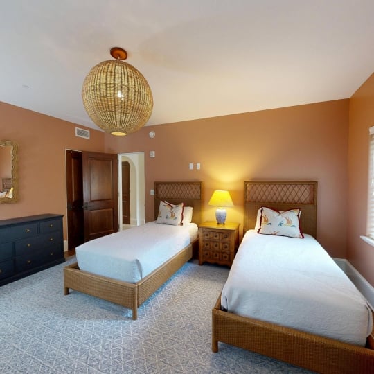 A warm bedroom with two twin beds separated by a side table