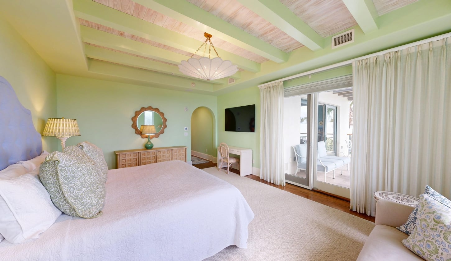 A spacious bedroom with a door leading out to a patio