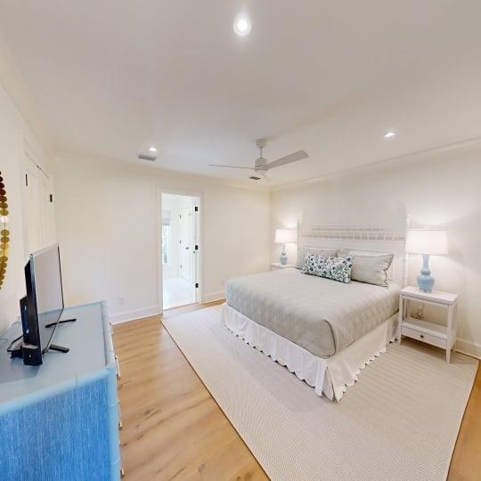 A spacious bedroom with a king bed and white rug