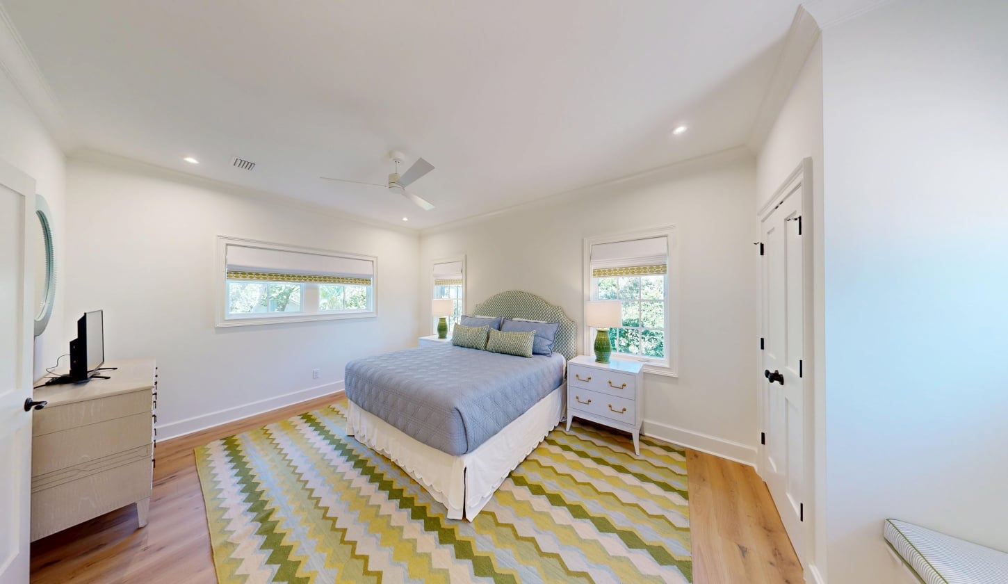 A bright bedroom with a green patterned rug