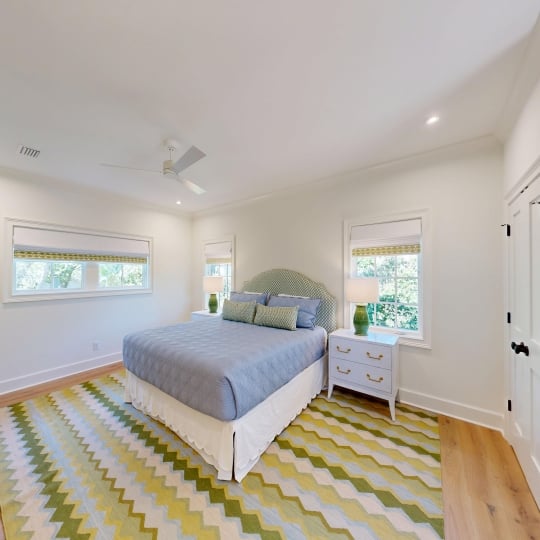 A bright bedroom with a green patterned rug