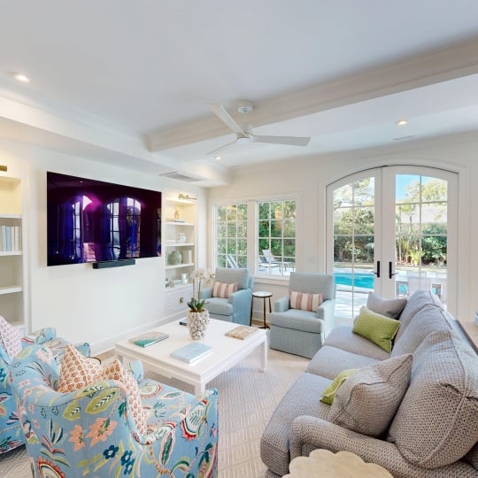 A seating area with a flat screen tv and a view of a pool outdoors