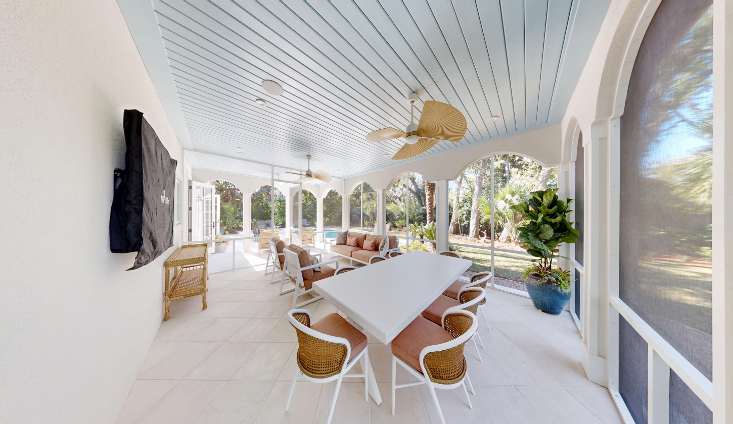 A screened patio with a flat screen tv and seating