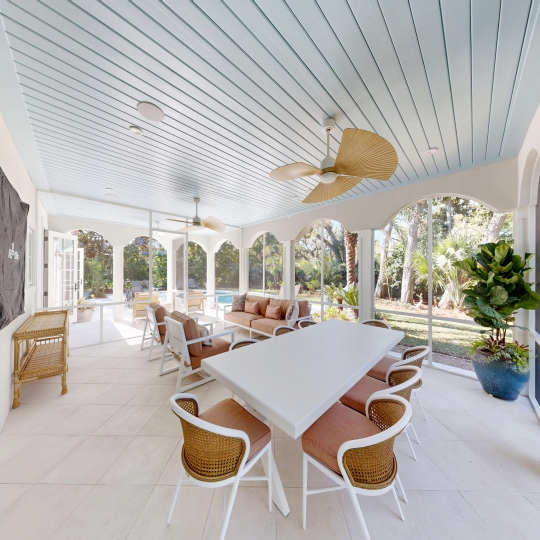 A screened patio with a flat screen tv and seating