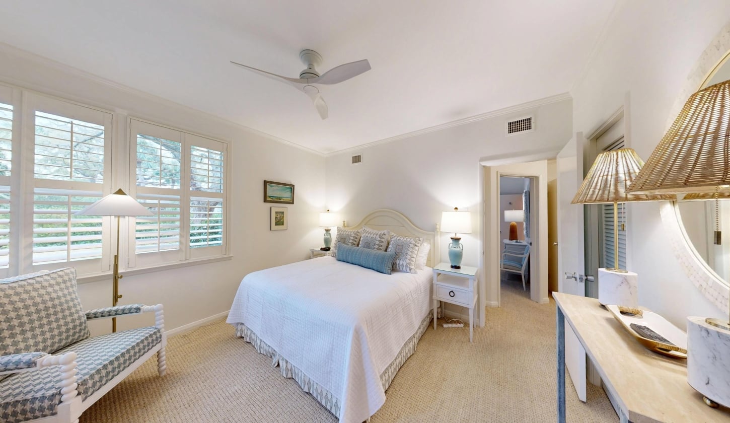 A white bed sites beside a window