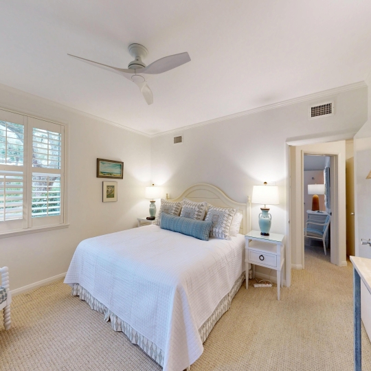 A white bed sites beside a window