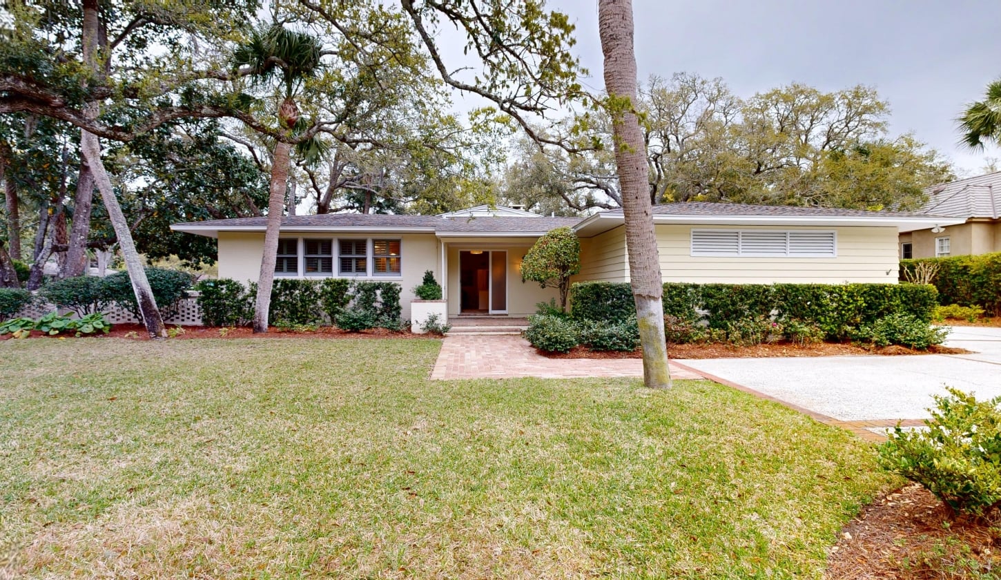 The front view of a cottage with trees behind it