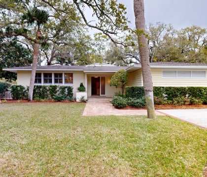 The front view of a cottage with trees behind it