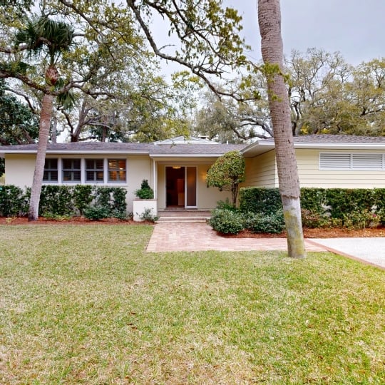 The front view of a cottage with trees behind it