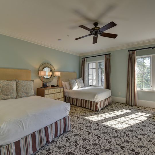 Bedroom with two queen beds and a white wicker chair
