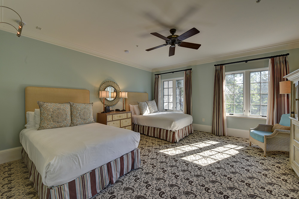 Bedroom with two queen beds and a white wicker chair