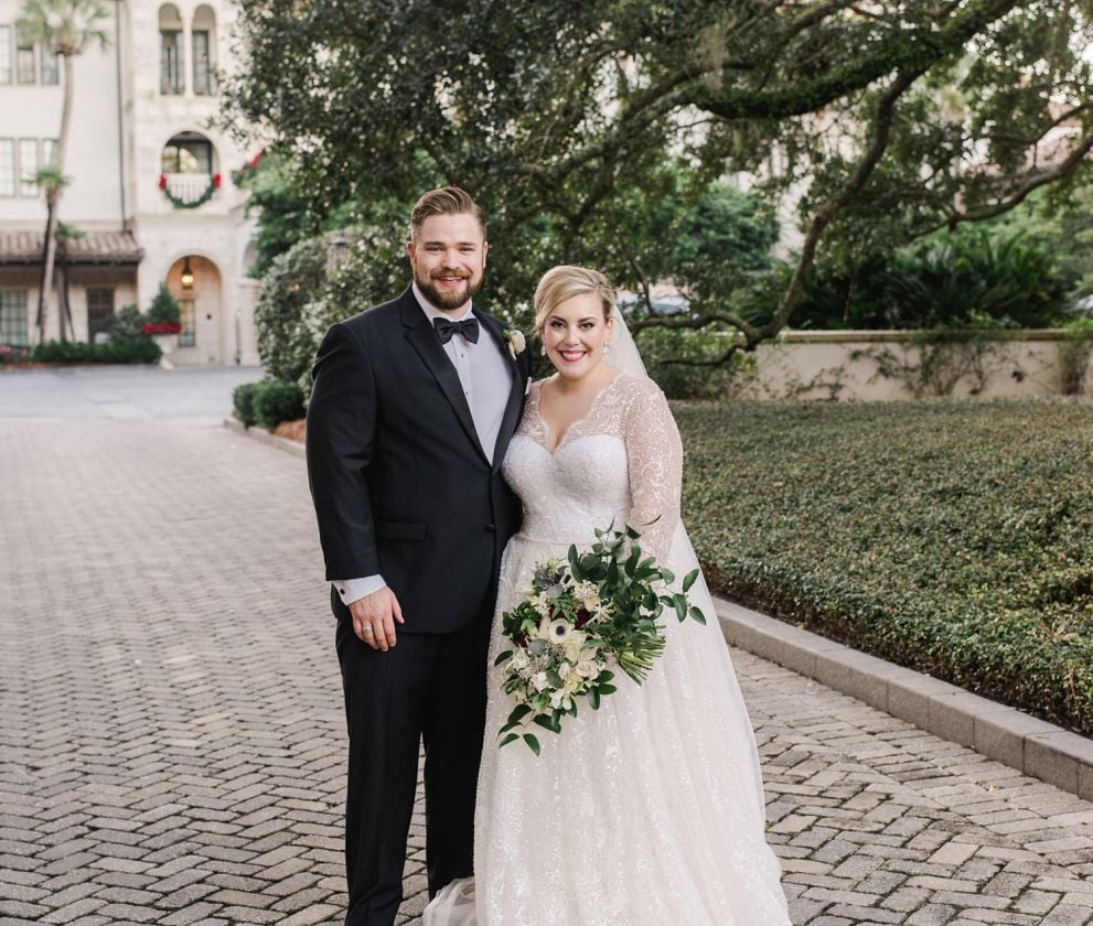 bride and groom posing near a park
