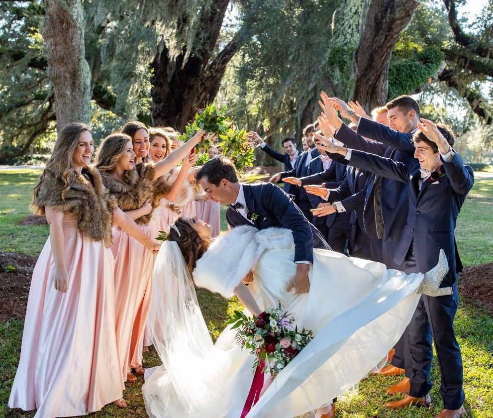 bride and groom kissing with their wedding party surrounding them