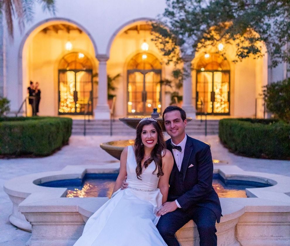bride and groom posing in front of a fountain