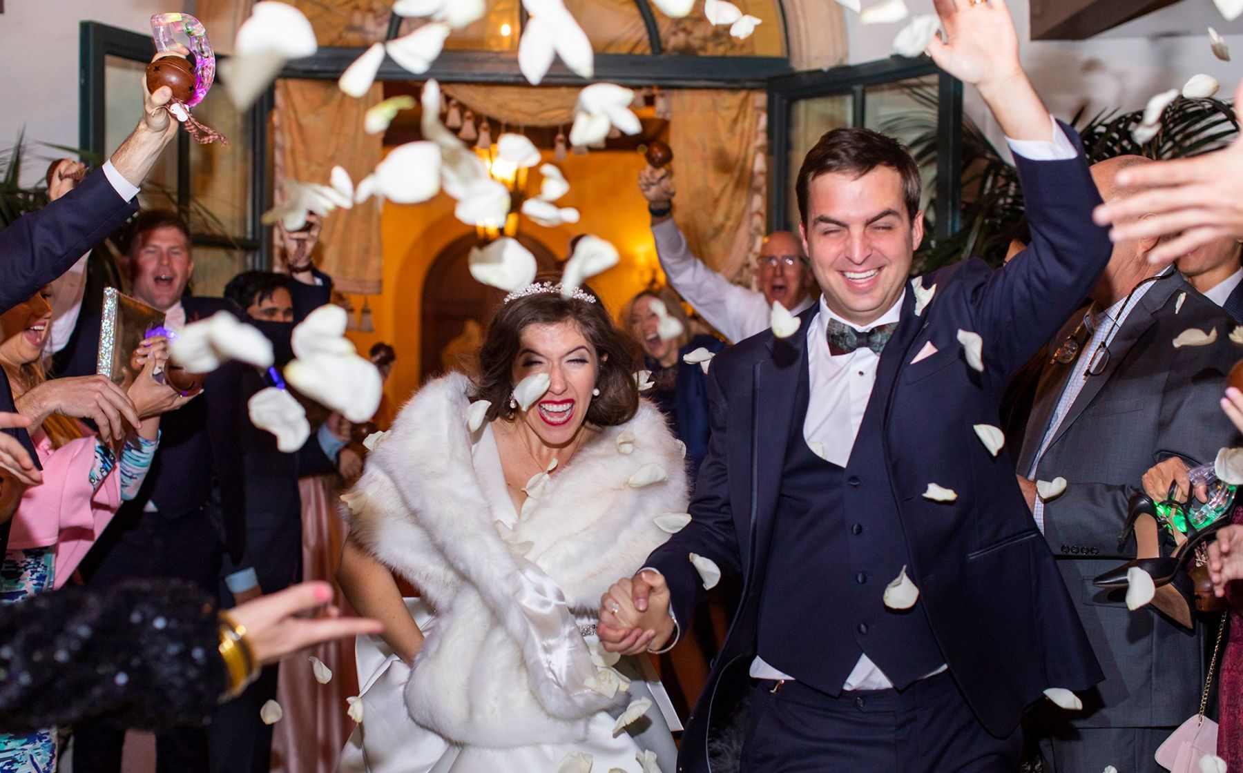 bride and groom leaving while flower petals are thrown at them