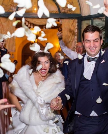 bride and groom leaving while flower petals are thrown at them