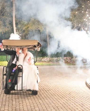 bride and groom driving away in a golf cart