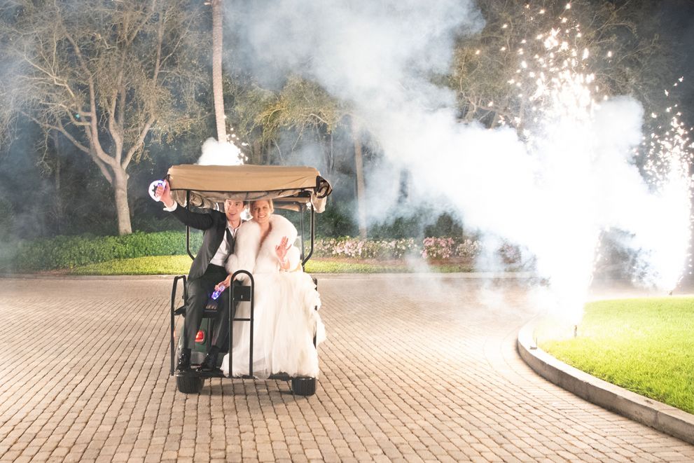 bride and groom driving away in a golf cart