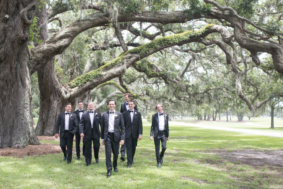 groom and groomsman walking through a park