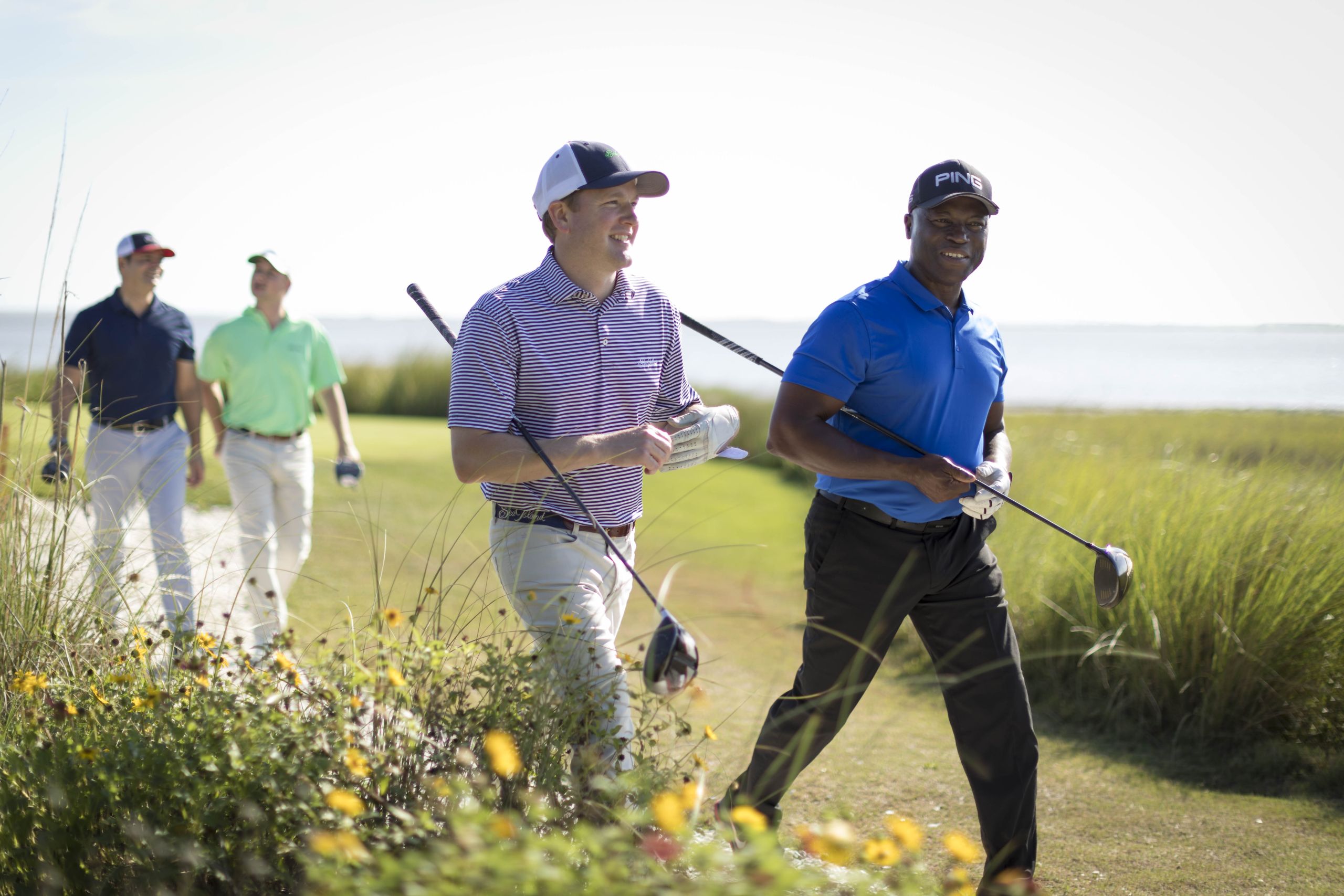 Four friends walking together after a coastal golf round