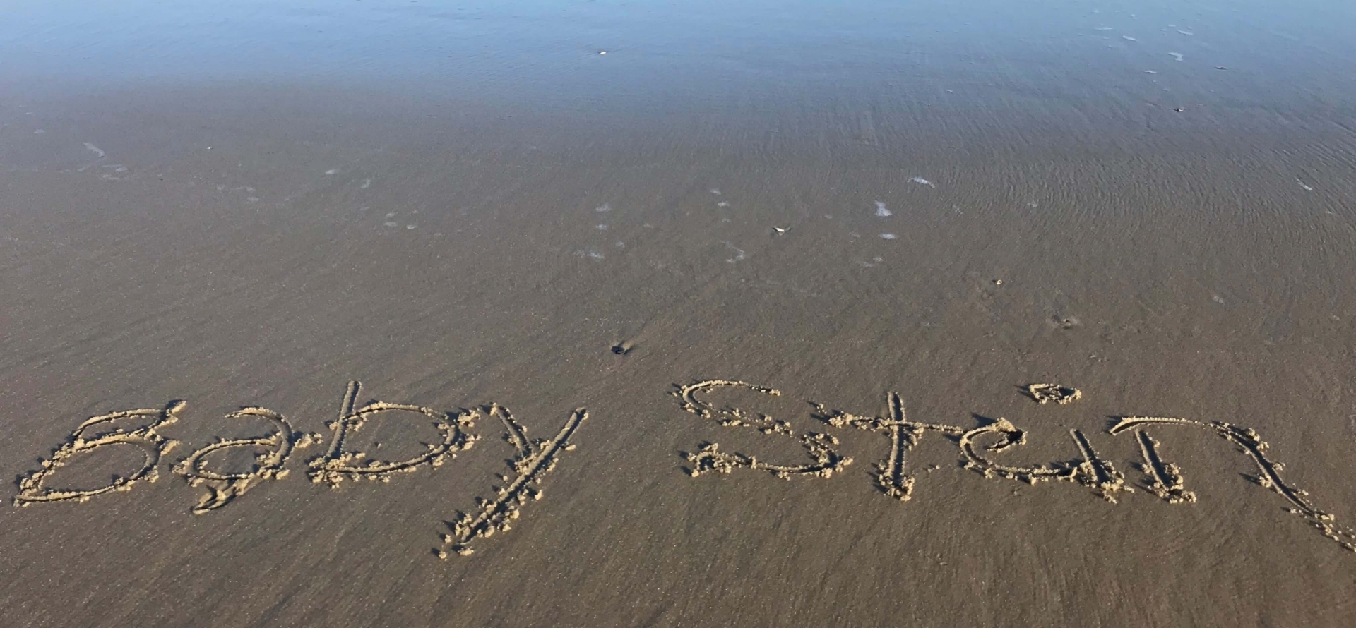 Writing in the sand at the beach. Babymoon