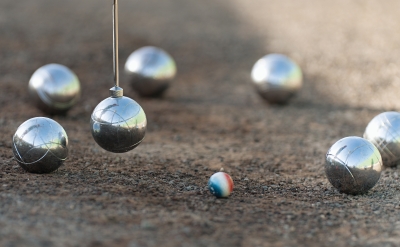 Petanque balls boules bowls on closeup on sand gravel court background, lifting the ball with a magnet