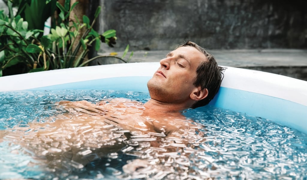 Portrait of a handsome Caucasian man lying in an ice bath. His eyes are closed, he is internalized and focuses on his breathing. Ice baths, when done properly, are known to boost metabolic health, immunity, and resilience.